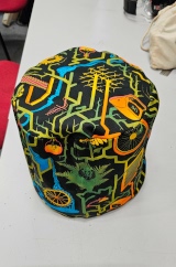 [Patterned fabric doorstop cover showing the top and zip on the back, with the doorstop inside it]