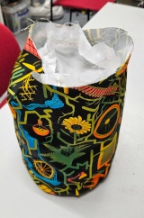 [Patterned fabric doorstop cover from the front, open at the top with the white ripstop PVC doorstop inside it]