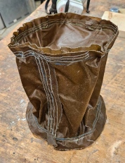 [Brown waxed canvas sewn in a cylinder shape, which is empty inside]