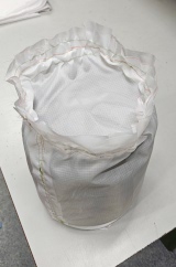 [White ripstop PVC doorstop sewn in a cylinder shape with brown waxed canvas and sand inside]